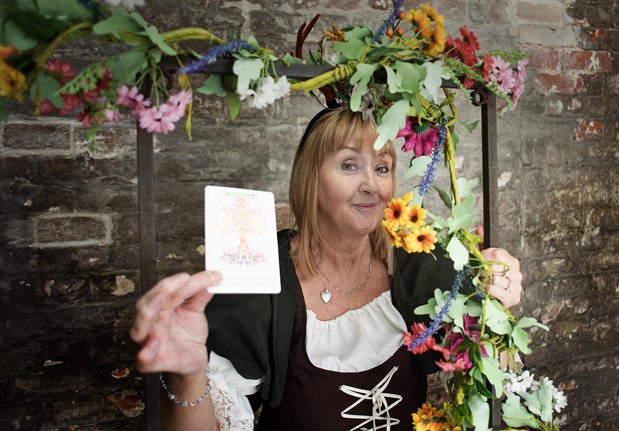 Rachel Goodall holding a positive affirmation card beneath a floral frame