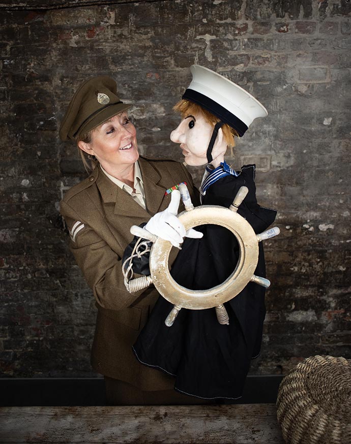 Rachel Goodall performing with a sailor puppet at a ship wheel